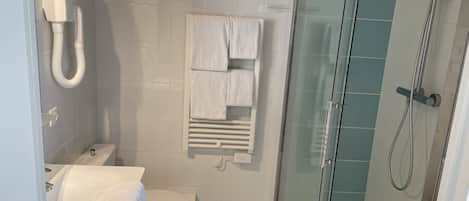 A modern bathroom with a toilet, a glass-enclosed shower, and a towel rack with multiple towels.