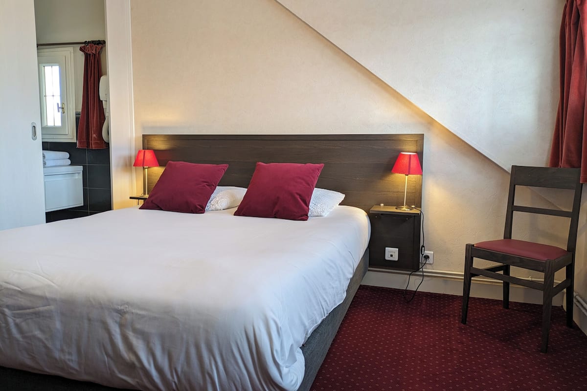Une chambre d’hôtel avec un grand lit, deux lampes de chevet, une chaise et une petite table.