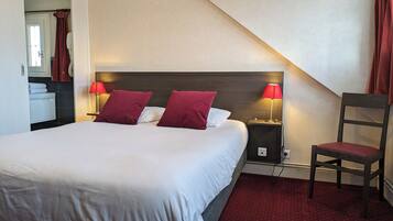 A hotel room with a large bed, two bedside lamps, a chair, and a small table.
