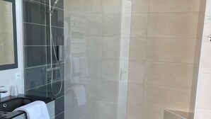 A modern bathroom with a glass-enclosed shower, a black vanity with a mirror, and a small trash bin. - Hôtel Le Saint Florent (Mont-pres-Chambord)