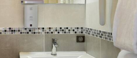 A modern bathroom with a sink, mirror, towel rack, and a soap dispenser.