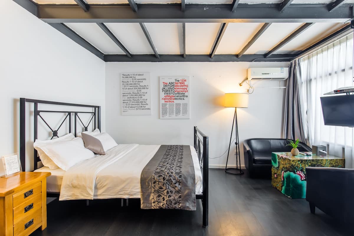 Ein modernes Hotelzimmer mit Bett, Schreibtisch, Stuhl, Fernseher und einem Fenster mit Vorhängen.