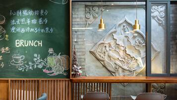 Interior de restaurante con menú en pizarra, sillas de madera y decorativos grabados en la pared.