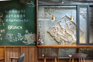 A restaurant interior with a chalkboard menu, wooden chairs, and decorative wall carvings. - Humble Inn Boutique Residence (Guilin)