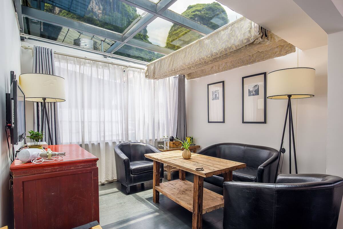 Ein Zimmer mit einem Holztisch, zwei schwarzen Ledersesseln, einem roten Schrank und einem Glas-Skylight in der Decke.