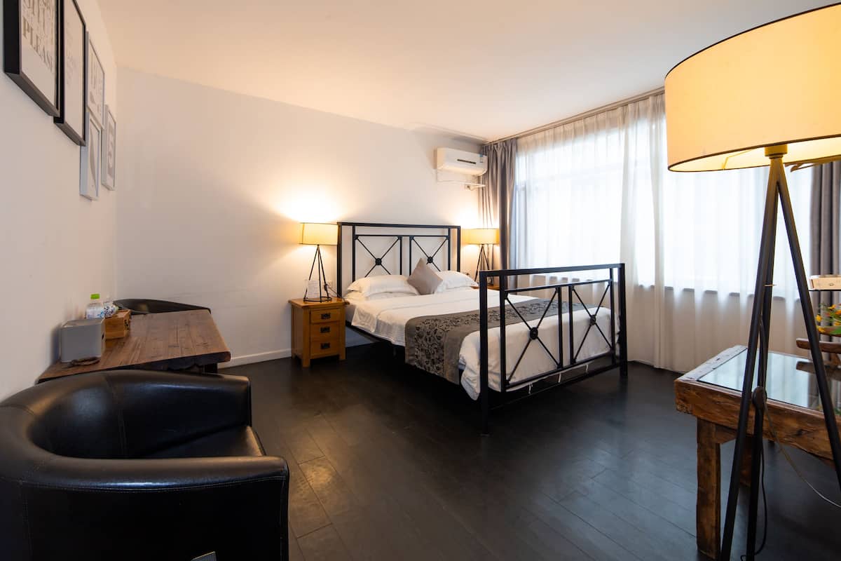 Ein Hotelzimmer mit einem Bett, Nachttischen, einem Schreibtisch, einem Sessel und einer Lampe.