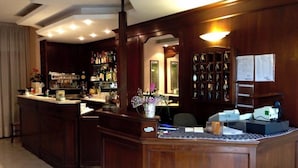 A bar area with wooden furnishings, a counter with a menu, and a display of bottles. - Osteria Dei Locandieri (Abbadia San Salvatore)