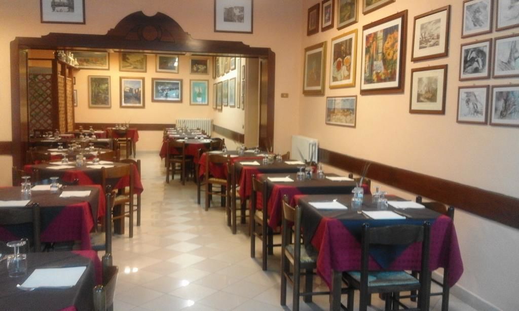 Een restaurant met gedekte tafels, kunstwerken aan de muur en een geruite vloer.