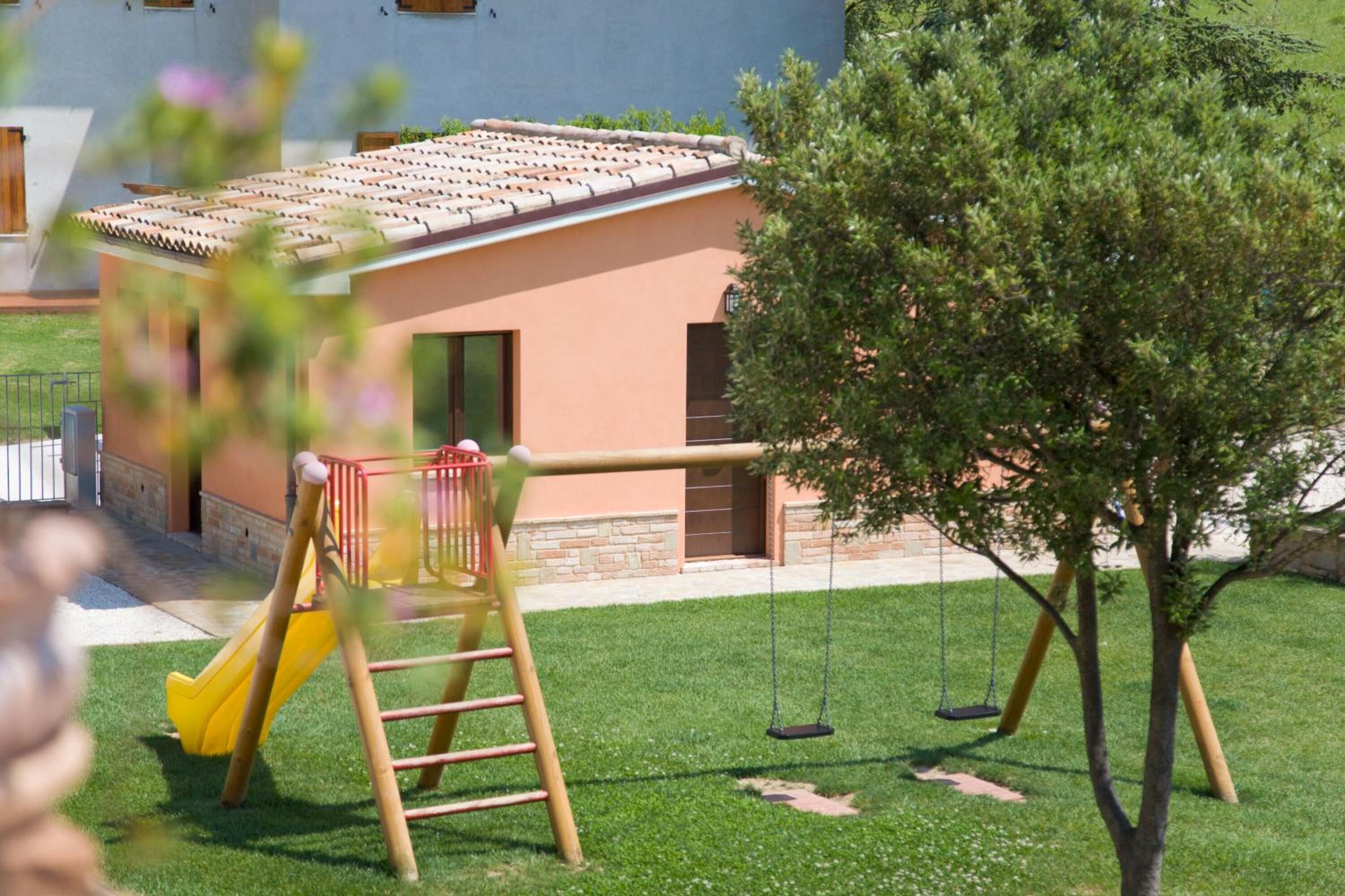 A playground with a slide, swings, and a small building.