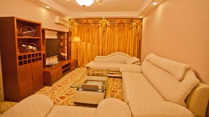 A living room with a sofa set, a wooden entertainment unit, and a chandelier. - YangShuo New Century Hotel (Guilin)