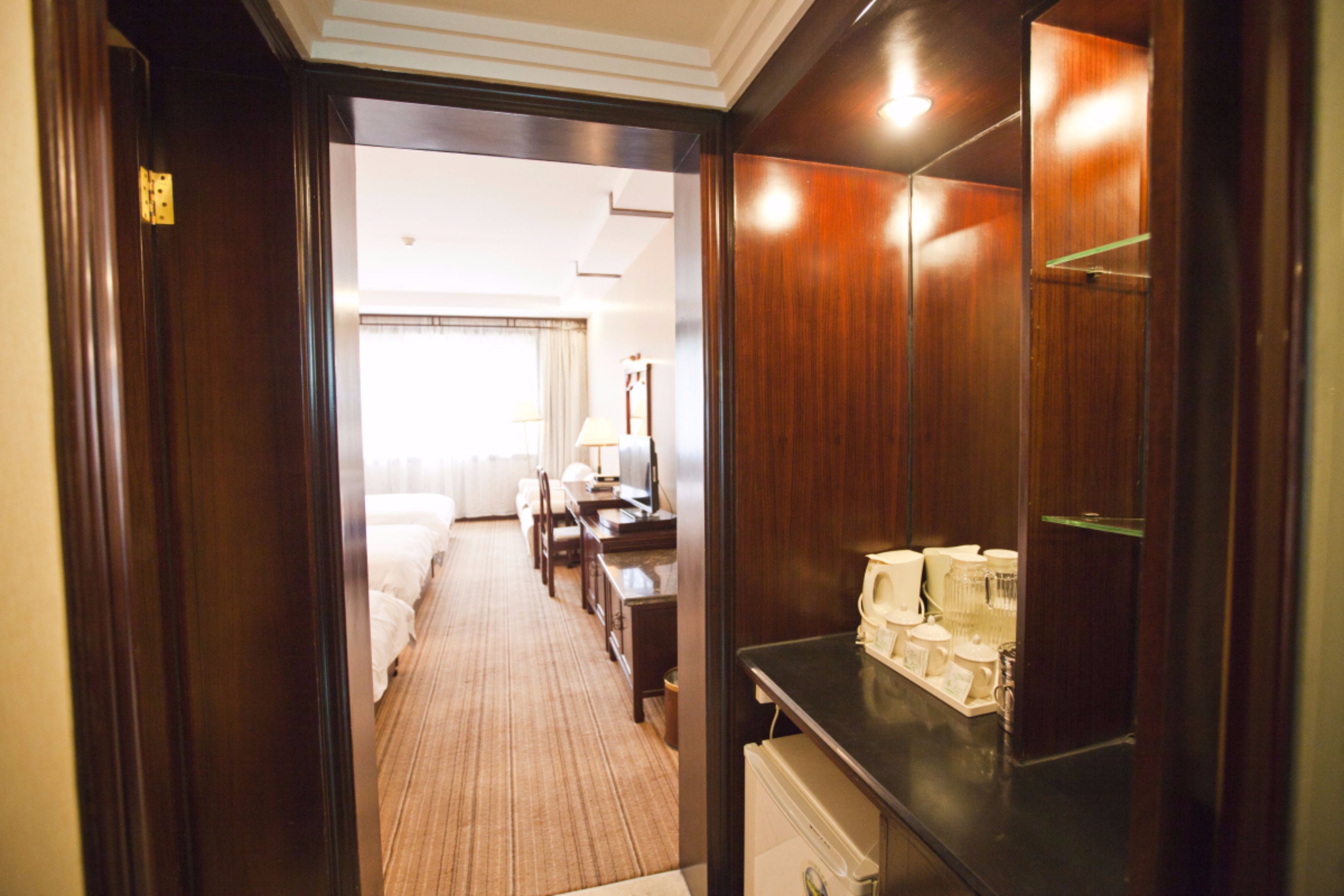 Un couloir d’hôtel avec un lit, un bureau et un comptoir sur lequel sont posés divers objets.