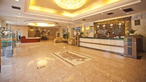 A spacious lobby with a reception desk, seating area, and a large chandelier. - YangShuo New Century Hotel (Guilin)