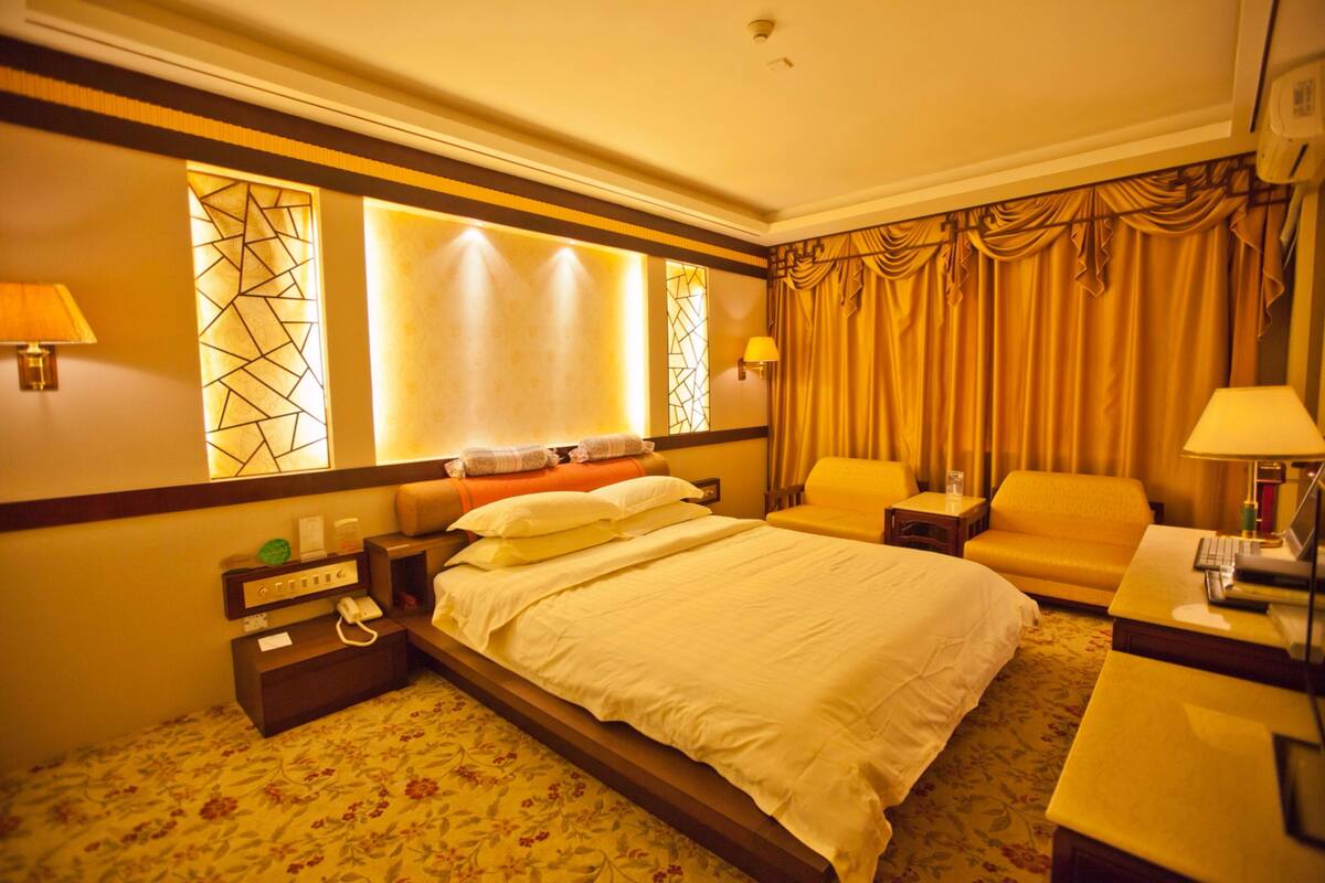A hotel room with a large bed, two chairs, a desk, and a small table.