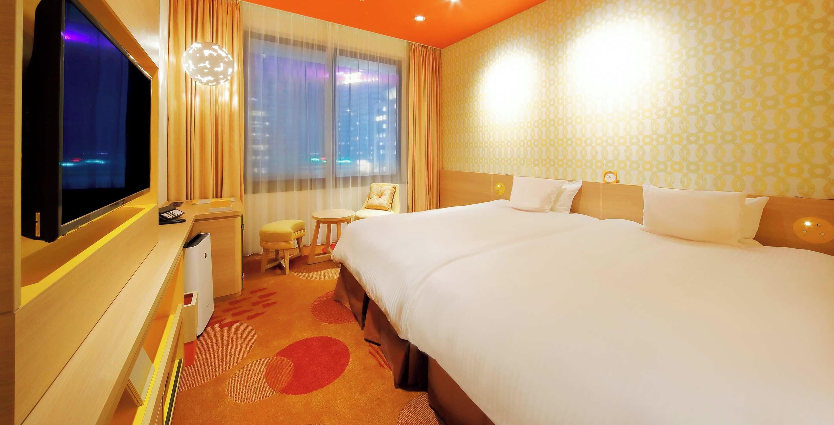 A hotel room with a large bed, a desk with a computer, a chair, and a TV.