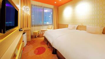 A hotel room with a large bed, a desk with a computer, a chair, and a TV.