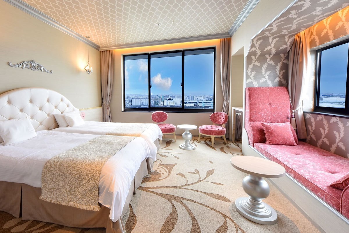 A hotel room with a large bed, a seating area with a view, and a small table.