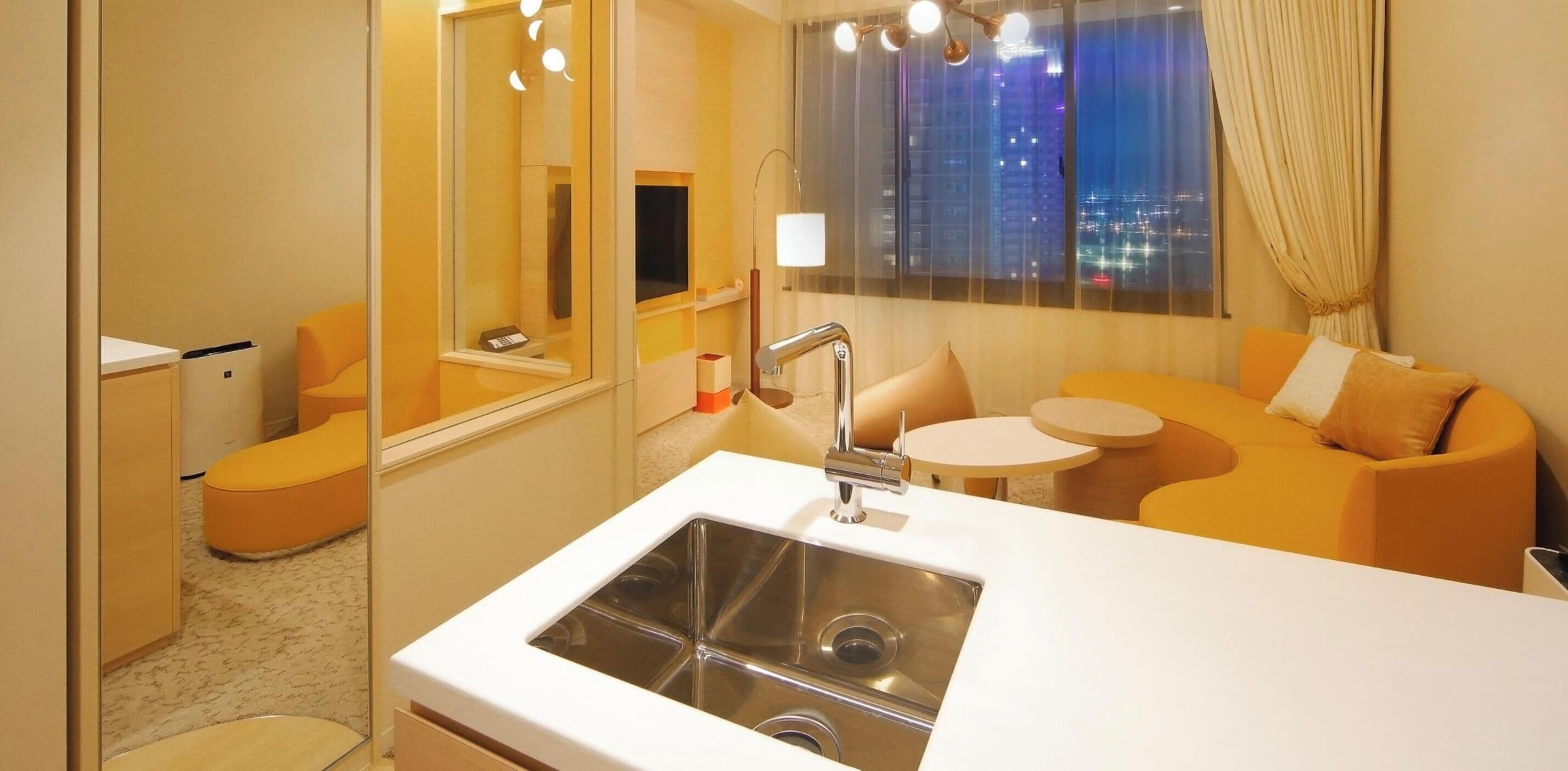 A modern bathroom with a sink, mirror, and a view of a cityscape at night.