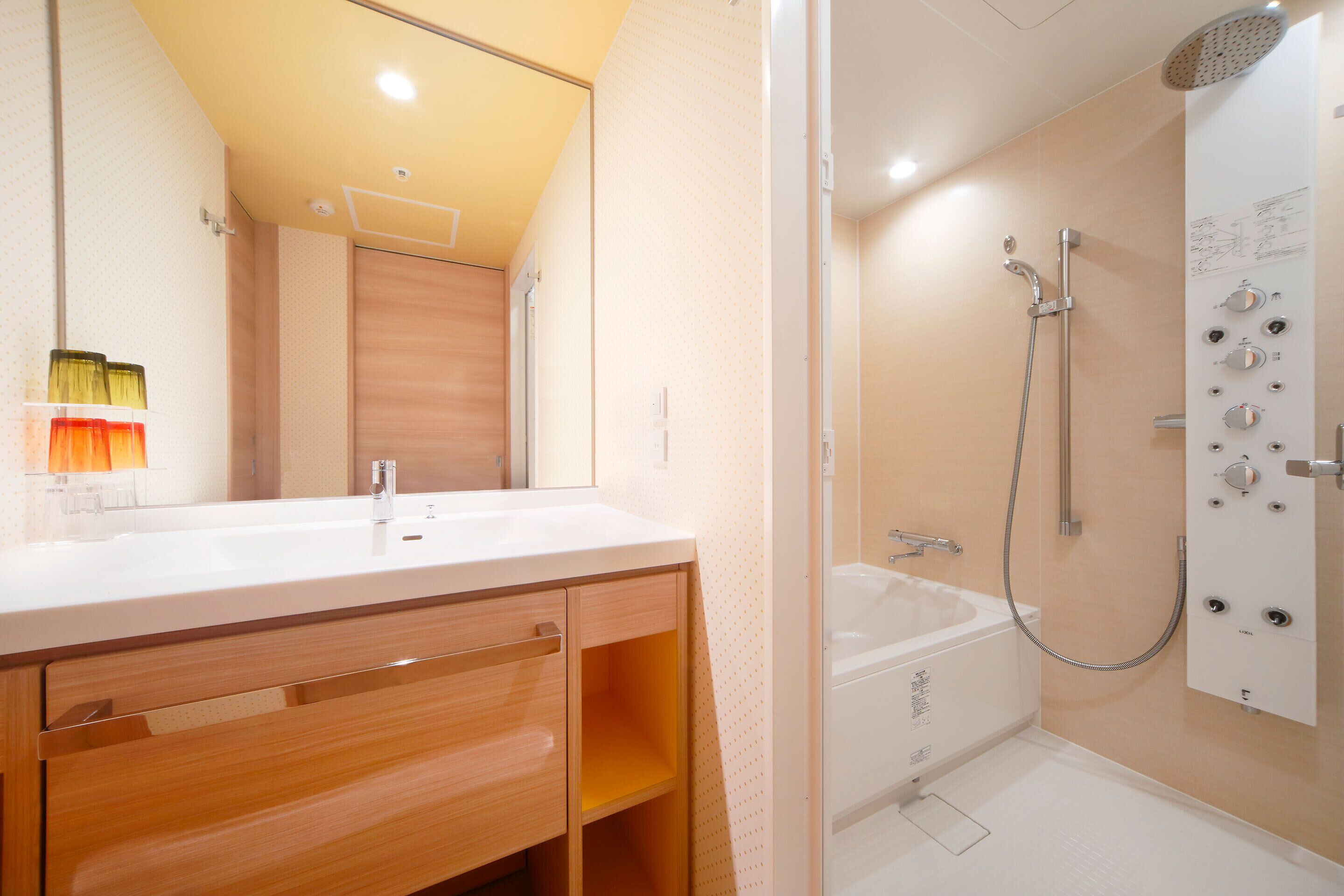 Une salle de bain moderne avec un double vasque, un meuble-lavabo en bois, une douche dotée de plusieurs commandes et une baignoire.