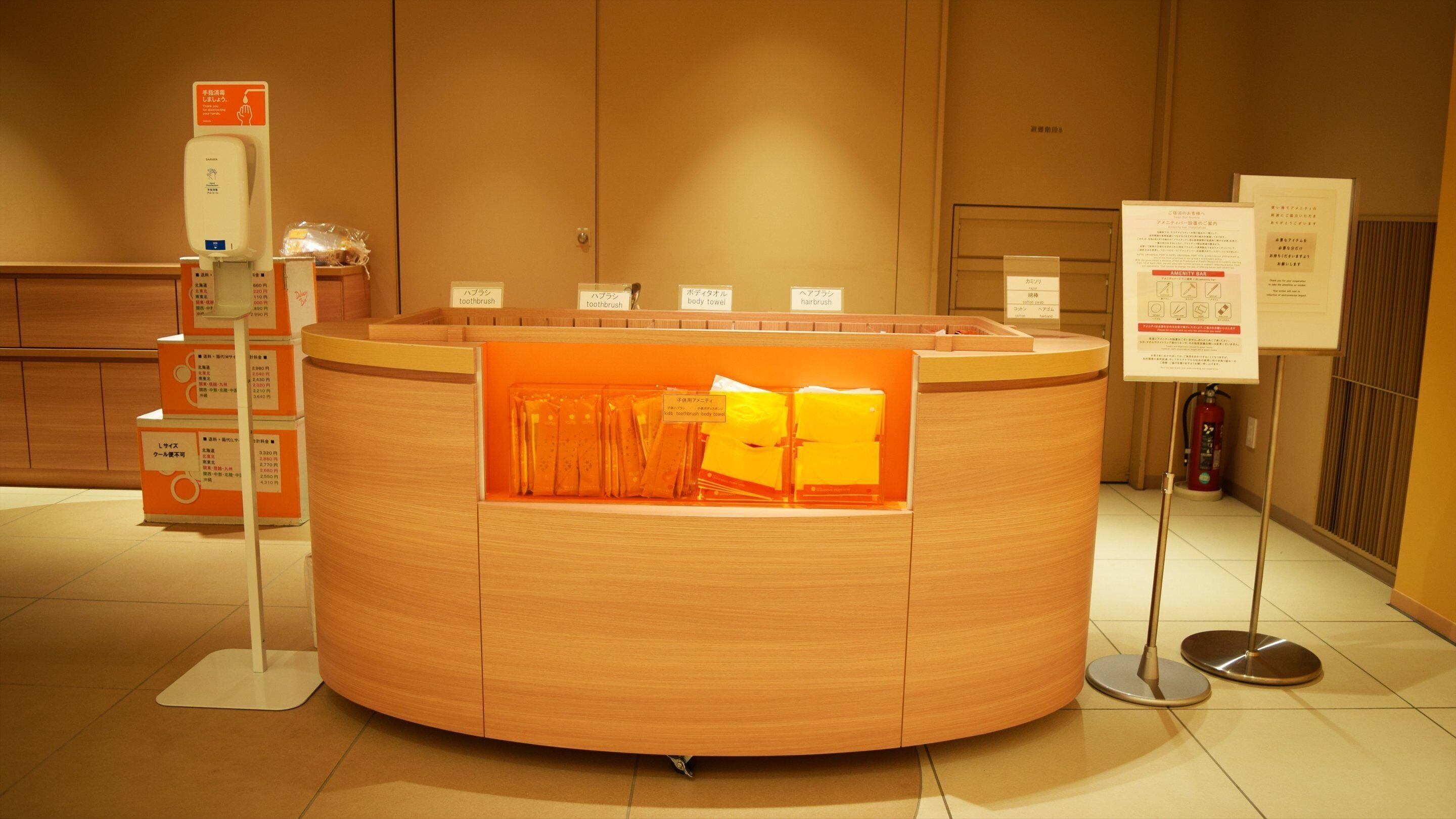 A reception desk with a counter, a hand sanitizer dispenser, and informational signs.