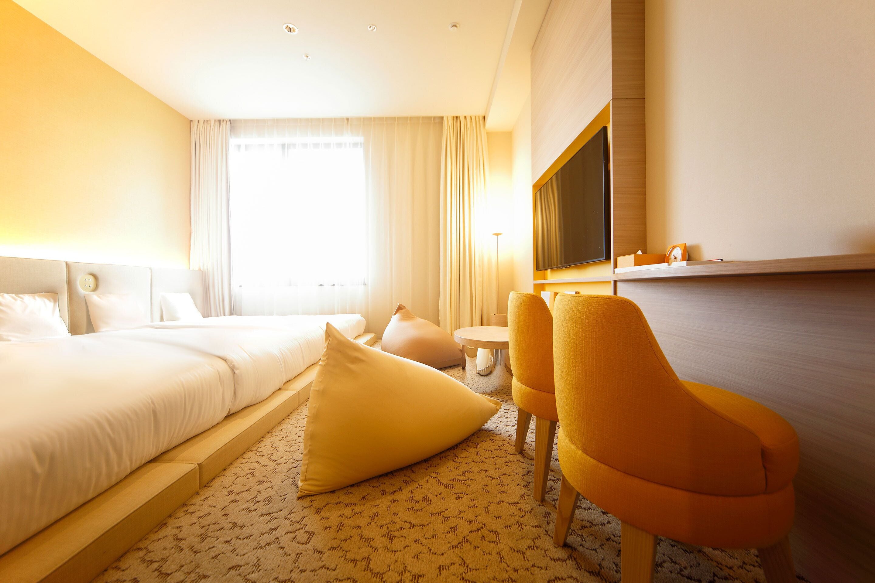 A hotel room with a bed, a sofa, a TV, and a small table.