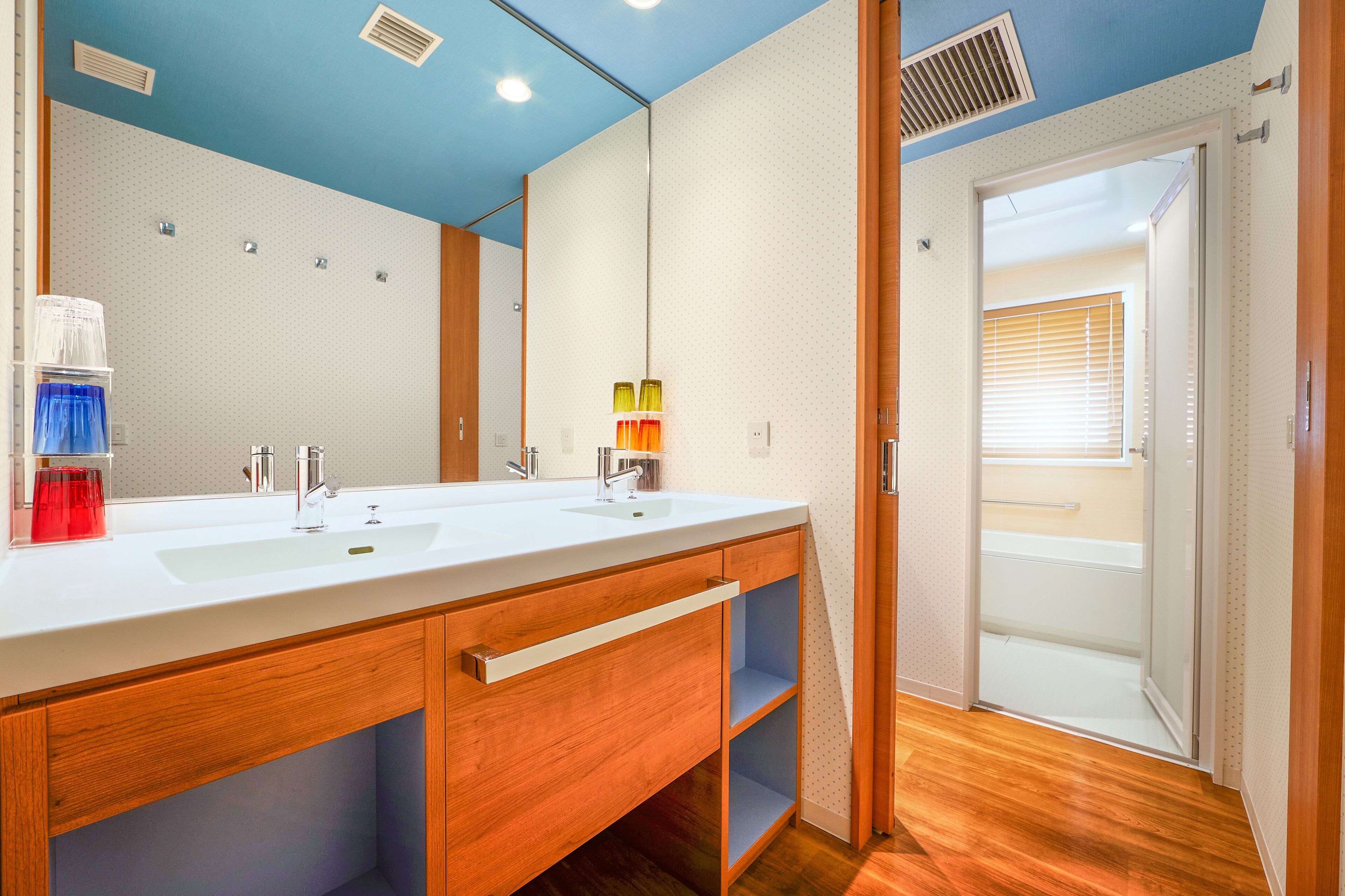 A modern bathroom with two sinks, wooden cabinets, and a shower area.