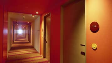 A hotel corridor with a carpeted floor, doors, and a number sign.