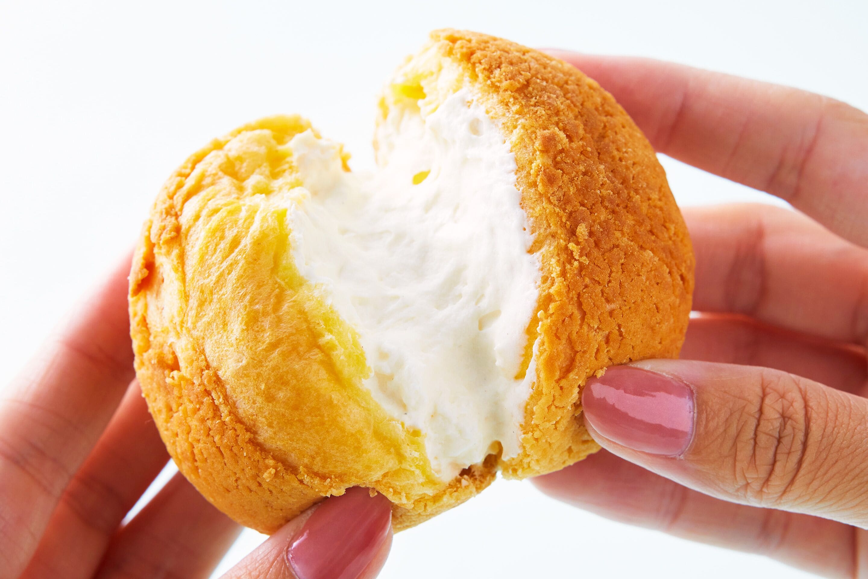 Una mano sosteniendo un pastel con relleno cremoso.