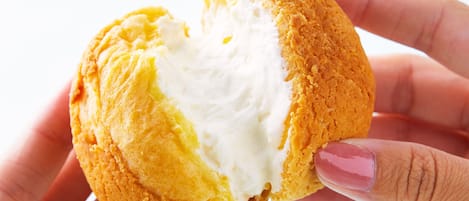 Una mano sosteniendo un pastel con relleno cremoso.