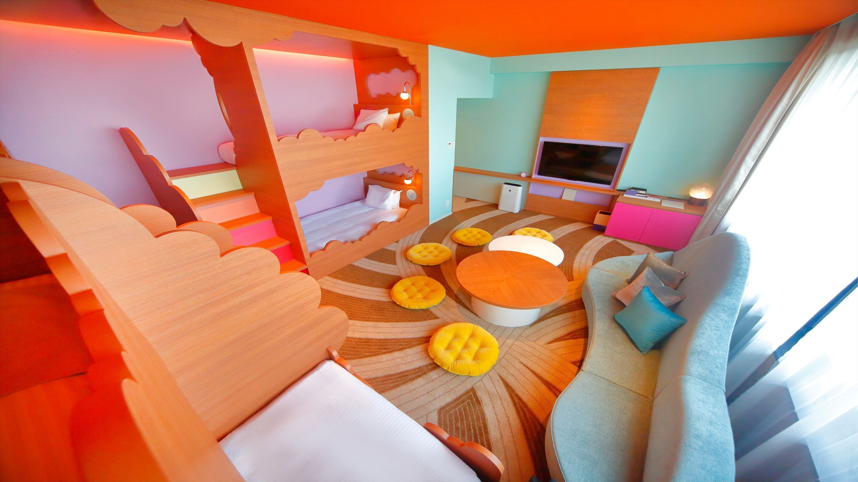 A room with a bunk bed, a sofa, a TV, and a pink cabinet.