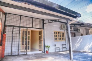 A covered outdoor area with a tiled entrance, a potted plant, and two chairs. - Maxi Home (Petaling Jaya)