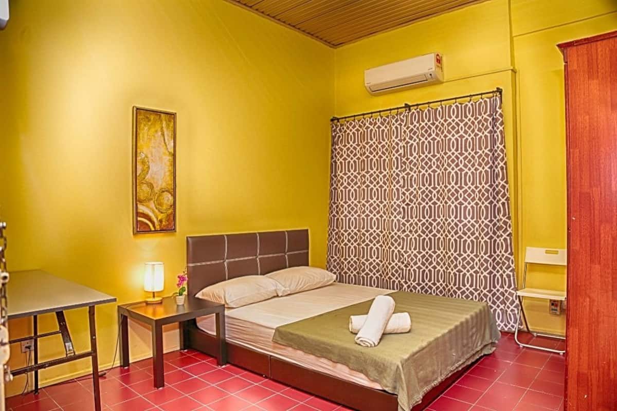 Una habitación con cama, escritorio, lámpara y cortina estampada.