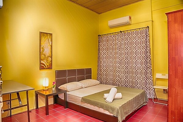 A room with a bed, a desk, a lamp, and a patterned curtain. - Maxi Home (Petaling Jaya)