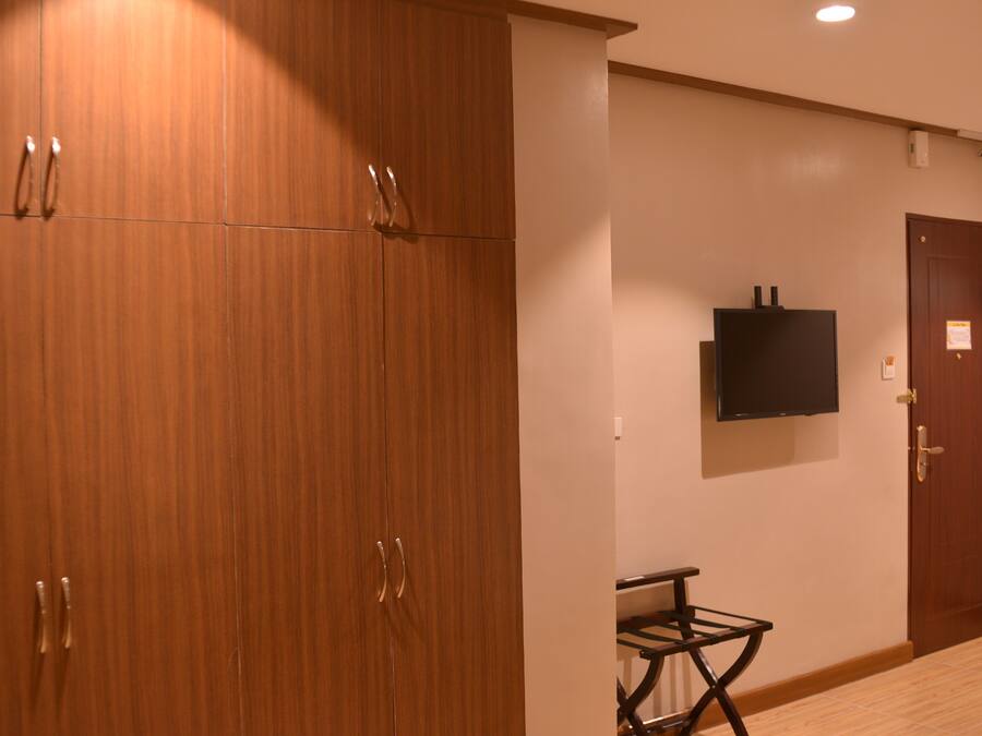 A hotel room with wooden wardrobes, a flat-screen TV, and a small table.