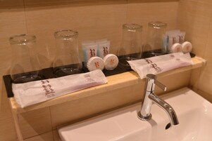 Un baño de hotel con lavamanos, espejo y artículos de aseo.