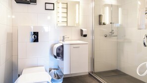A modern bathroom with a glass shower enclosure, a sink with a soap dispenser, and a towel rack. - Adventure Hotel Hof (Fagurholsmyri)