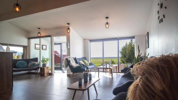 Ein großzügiger Wohnbereich mit großem Fenster, einer Couch, einem Couchtisch und einem Sessel.