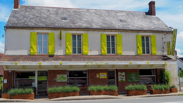 Un immeuble de deux étages avec une façade blanche et des volets jaunes.