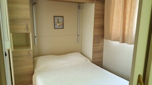 Un dormitorio con cama, armario de madera y un cuadro en la pared.