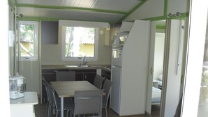 Una cocina compacta con una mesa de comedor y sillas, un refrigerador y un lavamanos.