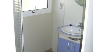 Un baño con ventana, lavamanos y espejo.