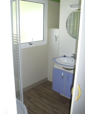 Un baño con ventana, lavamanos y espejo.