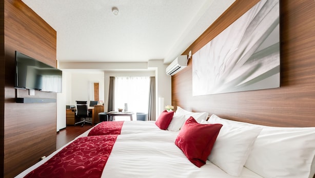 A hotel room with a large bed, a desk, a TV, and an air conditioning unit. - The One Osaka Nipponbashi East (Osaka)