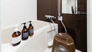 A bathroom with a bathtub, a stool, and two bottles of shampoo. - The One Osaka Nipponbashi East (Osaka)