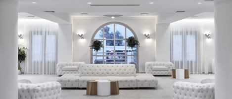 Ein großzügiges, modernes Interieur mit einer geräumigen Sitzecke, weißen Möbeln und außergewöhnlichen Pendelleuchten.