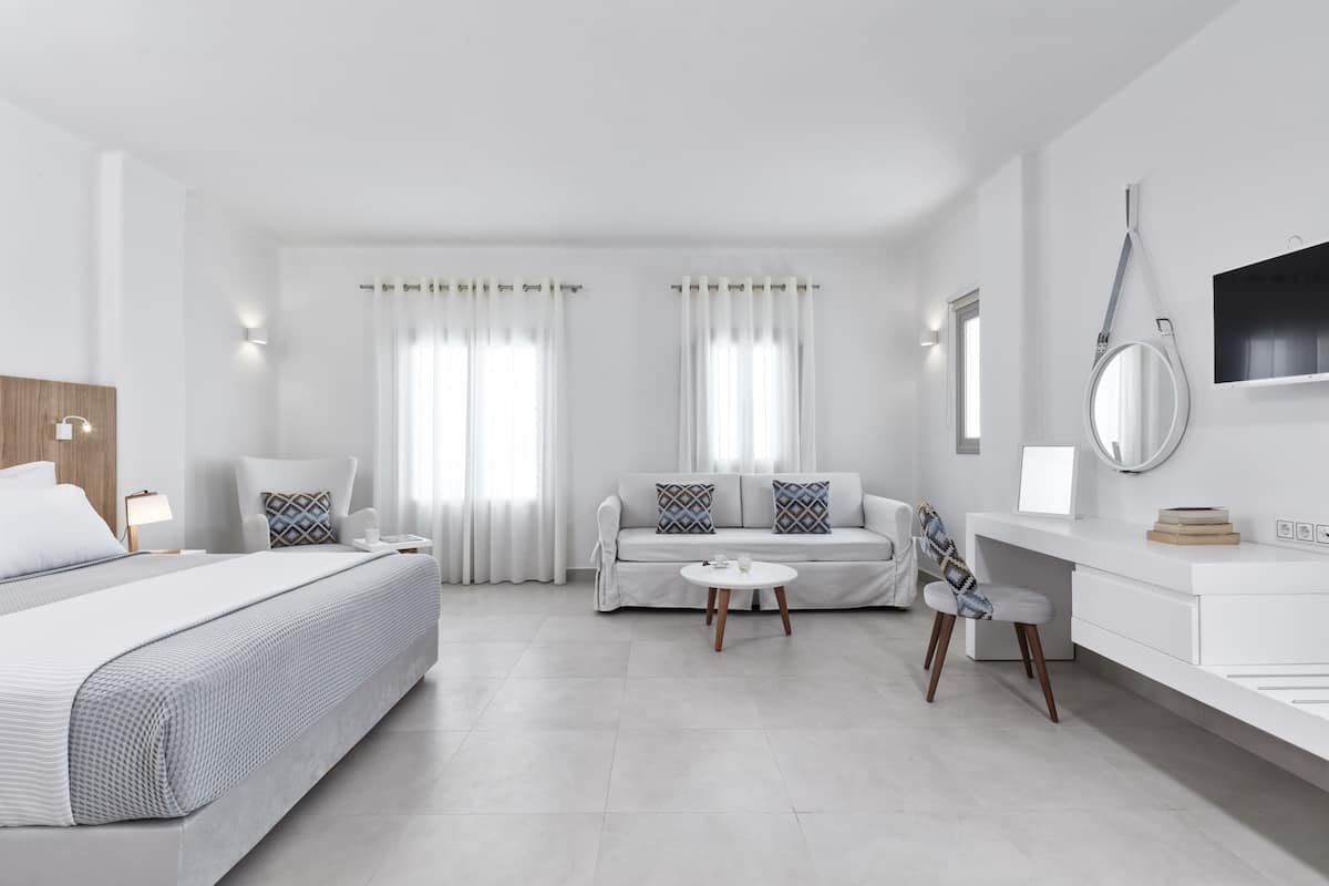 Une chambre d’hôtel moderne équipée d’un lit, d’un canapé, d’un bureau et d’une chaise.