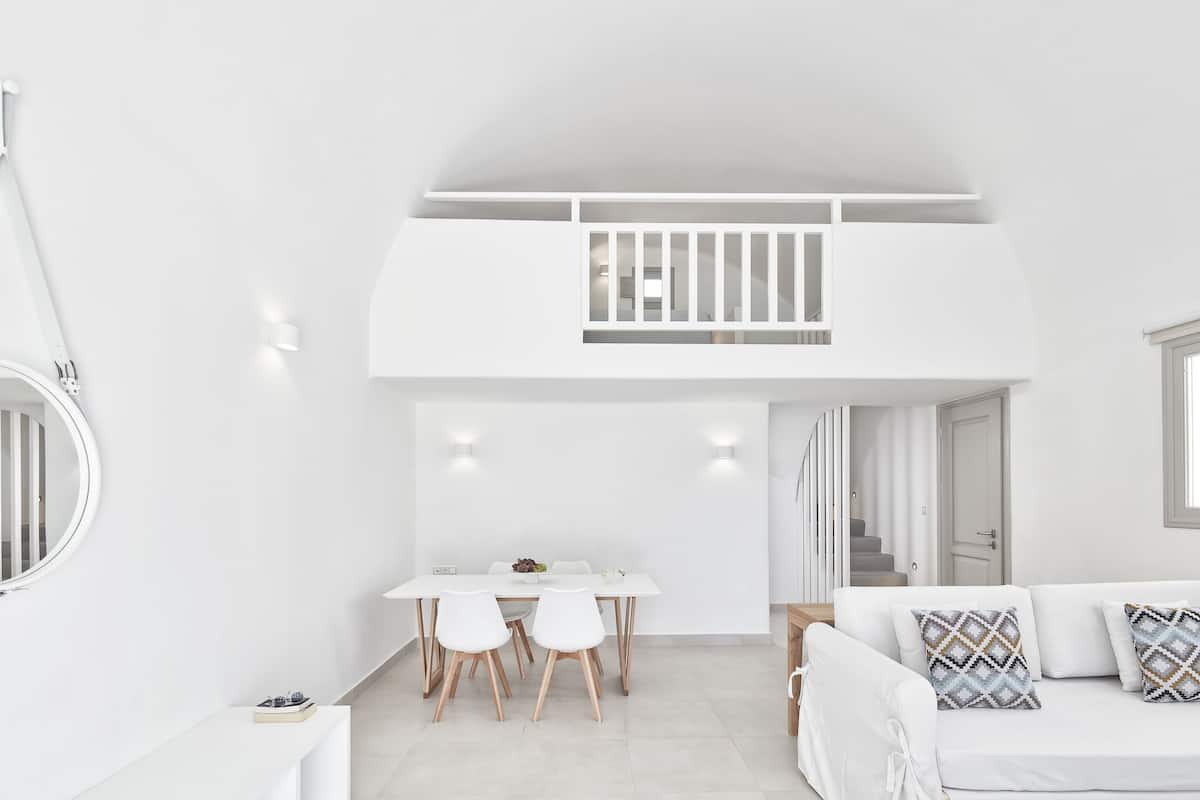 Un intérieur moderne et épuré, avec un espace repas, un canapé et un escalier.
