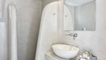 A modern bathroom with a freestanding bathtub, a large mirror, and a white sink with toiletries.