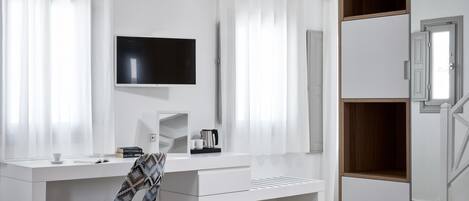 A modern, white room with a desk, chair, and a television mounted on the wall.