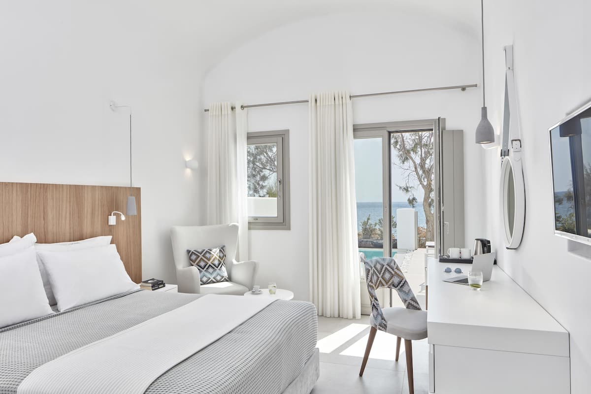 Une chambre d’hôtel moderne équipée d’un lit, d’un bureau, d’une chaise et offrant une vue sur la mer.