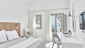 A modern hotel room with a bed, a desk, a chair, and a view of the sea.